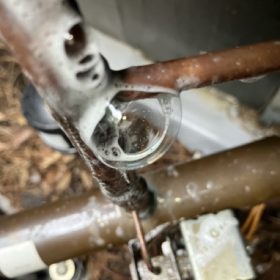 Close-up view of water bubbling on pipes for an HVAC contractor to repair.